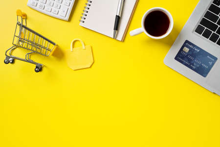 Top view of online shopping design concept with credit card, note, calculator and computer isolated on office yellow table background.の写真素材