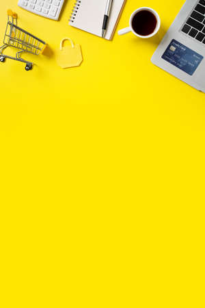 Online shopping concept. Top view of credit card purchase design concept with note, calculator and computer isolated on office yellow table background.の写真素材