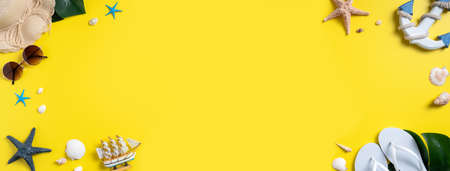 Summer beach design concept. Top view of holiday travel with shells, hat, slipper on yellow background.の写真素材