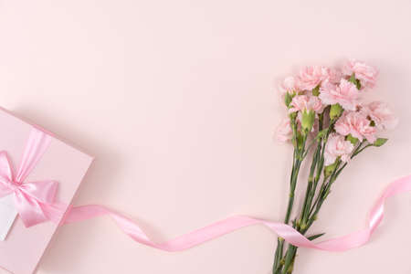Mother's day background concept. Top view design of holiday greeting gift with carnation bouquet on bright pink table backgroundの写真素材