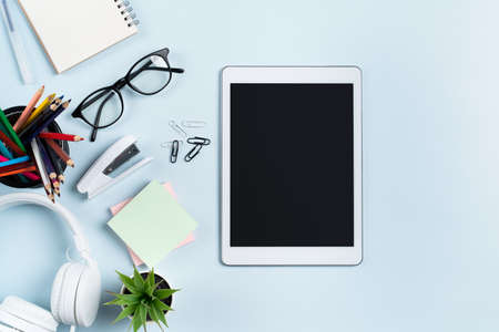 Online learning design concept. Top view of student table with tablet, headphone and stationeries on...