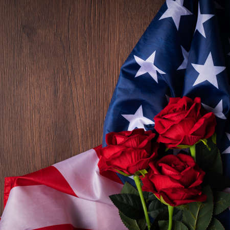Concept of US Independence day or Memorial day. National flag and red rose over dark wooden table background.の写真素材