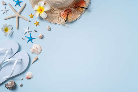 Summer beach background design concept. Top view of holiday travel with shells, hat, slipper on blue...