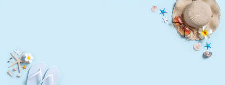 Summer beach background design concept. Top view of holiday travel with shells, hat, slipper on blue background.の写真素材