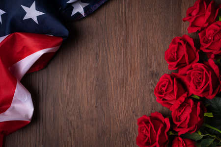 Concept of US Independence day or Memorial day. National flag and red rose over dark wooden table...