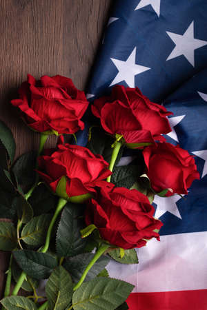 Concept of US Independence day or Memorial day. National flag and red rose over dark wooden table background.の写真素材