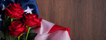 Concept of US Independence day or Memorial day. National flag and red rose over dark wooden table background.の写真素材