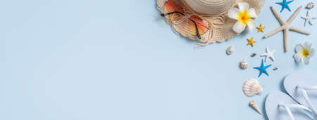Summer beach background design concept. Top view of holiday travel with shells, hat, slipper on blue...