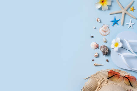 Summer beach background design concept. Top view of holiday travel with shells, hat, slipper on blue background.の写真素材