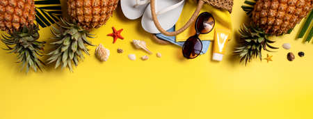 Summer fruit background design concept. Top view of holiday travel beach with shells, pineapple and palm leaves on yellow background.の写真素材