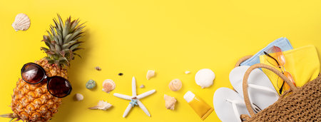 Summer fruit background design concept. Top view of holiday travel beach with shells, pineapple and palm leaves on yellow background.の写真素材