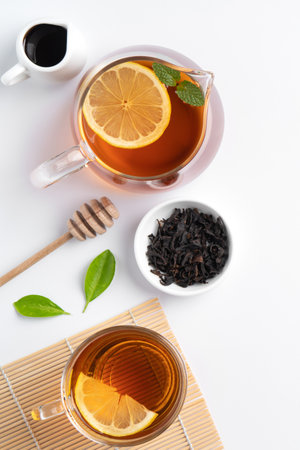 Design concept top view of honey black tea with yellow lemon and mint leaf on white table background.の写真素材
