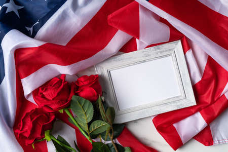 Concept of US Independence day or Memorial day. National flag and red rose over bright marble table background with picture frame.の写真素材