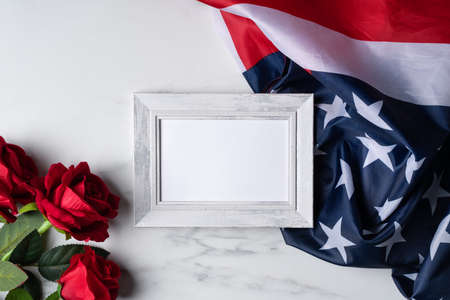 Concept of US Independence day or Memorial day. National flag and red rose over bright marble table background with picture frame.の写真素材