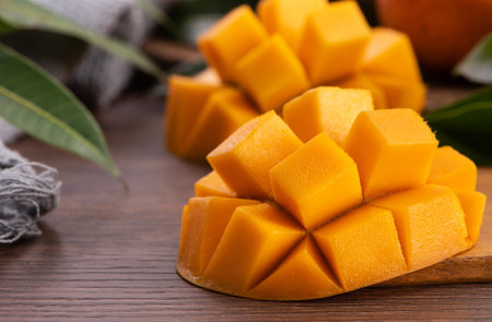 Mango. Close up of fresh ripe mango fruit with leaves over dark wooden table background with green leaves.の写真素材