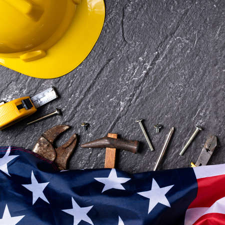 Top view design concept of American Labor Day with working tools on slate table background.