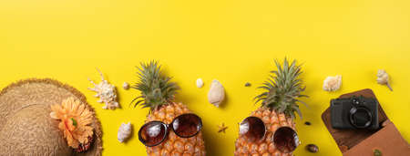 Summer fruit background design concept. Top view of holiday travel beach with shells, pineapple and palm leaves on yellow background.の写真素材