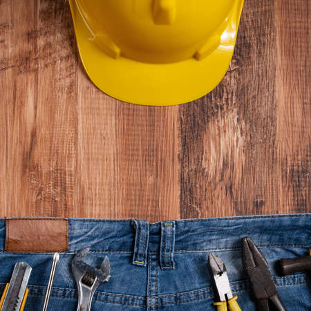 Top view design concept of Labor Day with working tools and jeans on wooden table background.