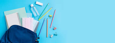 Top view of blue backpack with school stationery over blue table background, back to school design concept.の写真素材