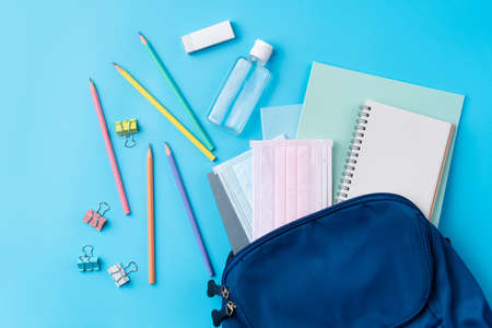 Top view of blue backpack with school stationery over blue table background, back to school design concept.の写真素材