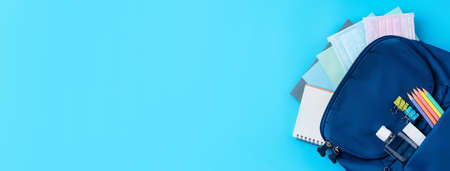 Top view of blue backpack with school stationery over blue table background, back to school design...