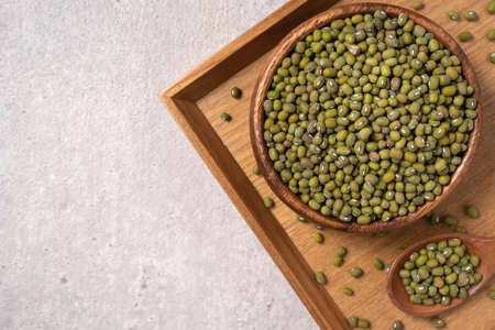 Top view of raw mung bean in a bowl on wooden table background.の写真素材