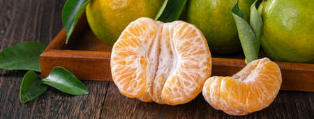 Fresh green tangerine mandarin orange with fresh leaves on dark wooden table with black background harvest concept.の写真素材