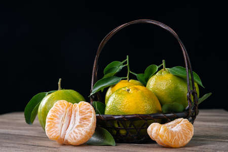 Fresh green tangerine mandarin orange with fresh leaves on dark wooden table with black background harvest concept.の写真素材