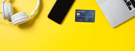 Top view of online shopping concept with credit card, smart phone and computer isolated on office yellow table background.の写真素材