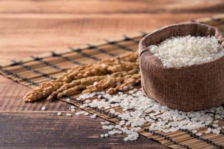 Raw white polished milled edible rice on wooden table background in a bowl, organic design concept.の写真素材