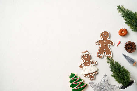 Top view of decorated Christmas gingerbread cookies with decorations on white table background with...