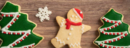 Top view of decorated Christmas gingerbread cookies with decorations on wooden table background with...