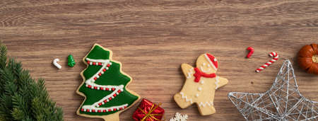 Top view of decorated Christmas gingerbread cookies with decorations on wooden table background with...