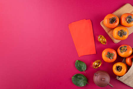 Top view of fresh sweet persimmons kaki with leaves on red table background for Chinese lunar new year fruit design concept, the word means spring is coming.の写真素材