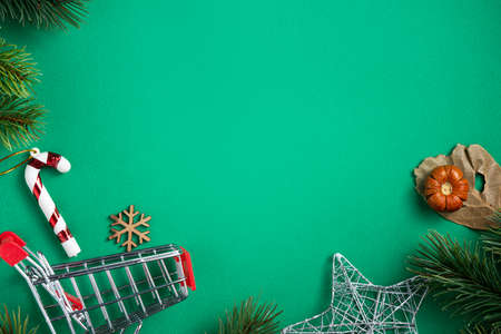 Top view of Christmas shopping design concept with gift box and shopping cart on green table...