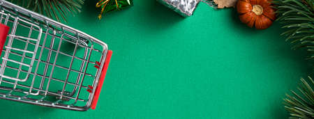 Top view of Christmas shopping design concept with gift box and shopping cart on green table backgroundの写真素材