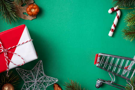 Top view of Christmas shopping design concept with gift box and shopping cart on green table backgroundの写真素材