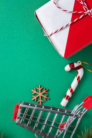 Top view of Christmas shopping design concept with gift box and shopping cart on green table backgroundの写真素材