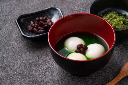 Close up of matcha big tangyuan (tang yuan) with sweet matcha soup in a bowl on wooden table background for festival food.の写真素材