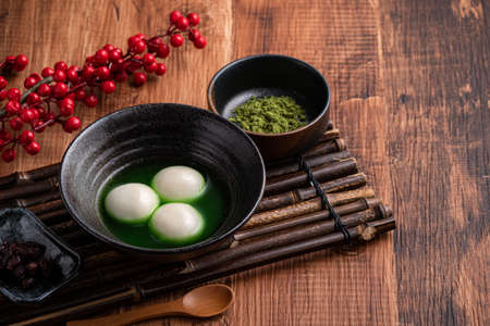 Close up of matcha big tangyuan (tang yuan) with sweet matcha soup in a bowl on wooden table background for festival food.の写真素材