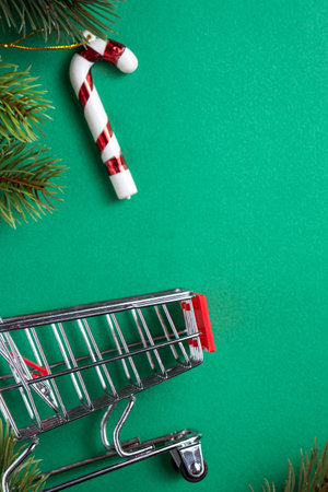Top view of Christmas shopping design concept with gift box and shopping cart on green table backgroundの写真素材