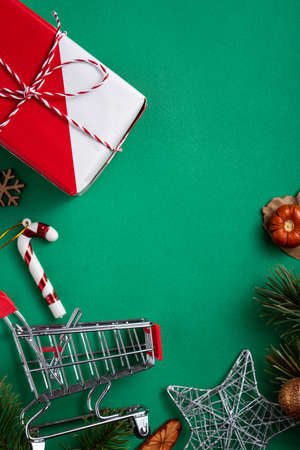 Top view of Christmas shopping design concept with gift box and shopping cart on green table backgroundの写真素材