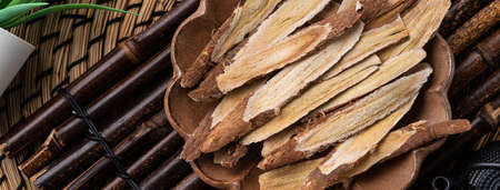 Top view of Chinese traditional herbal medicine Astragalus root on wooden table background.