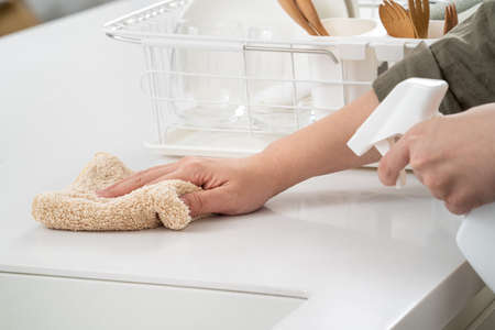 Woman housewife is doing the spring cleaning at home kitchen with using rag, spraying bottle cleaner to wipe the counter table surface.の写真素材