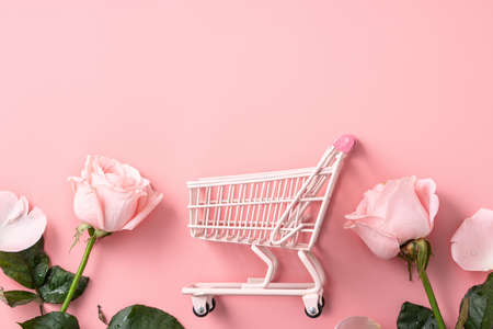 Valentine's Day shopping design concept background with pink rose flower and cart on pink table backgroundの写真素材