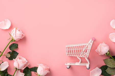 Valentine's Day shopping design concept background with pink rose flower and cart on pink table backgroundの写真素材