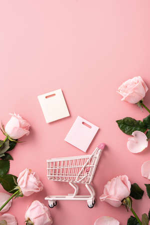 Valentine's Day shopping design concept background with pink rose flower and cart on pink table backgroundの写真素材