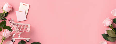 Valentine's Day shopping design concept background with pink rose flower and cart on pink table backgroundの写真素材
