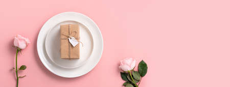Top view of Valentine's Day gift and meal design concept background with pink rose flower on pink table backgroundの写真素材