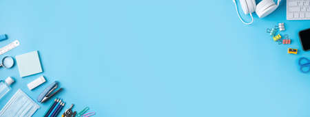 Online learning and back to school design concept. Top view of student table with headphone and stationery on blue table background.の写真素材